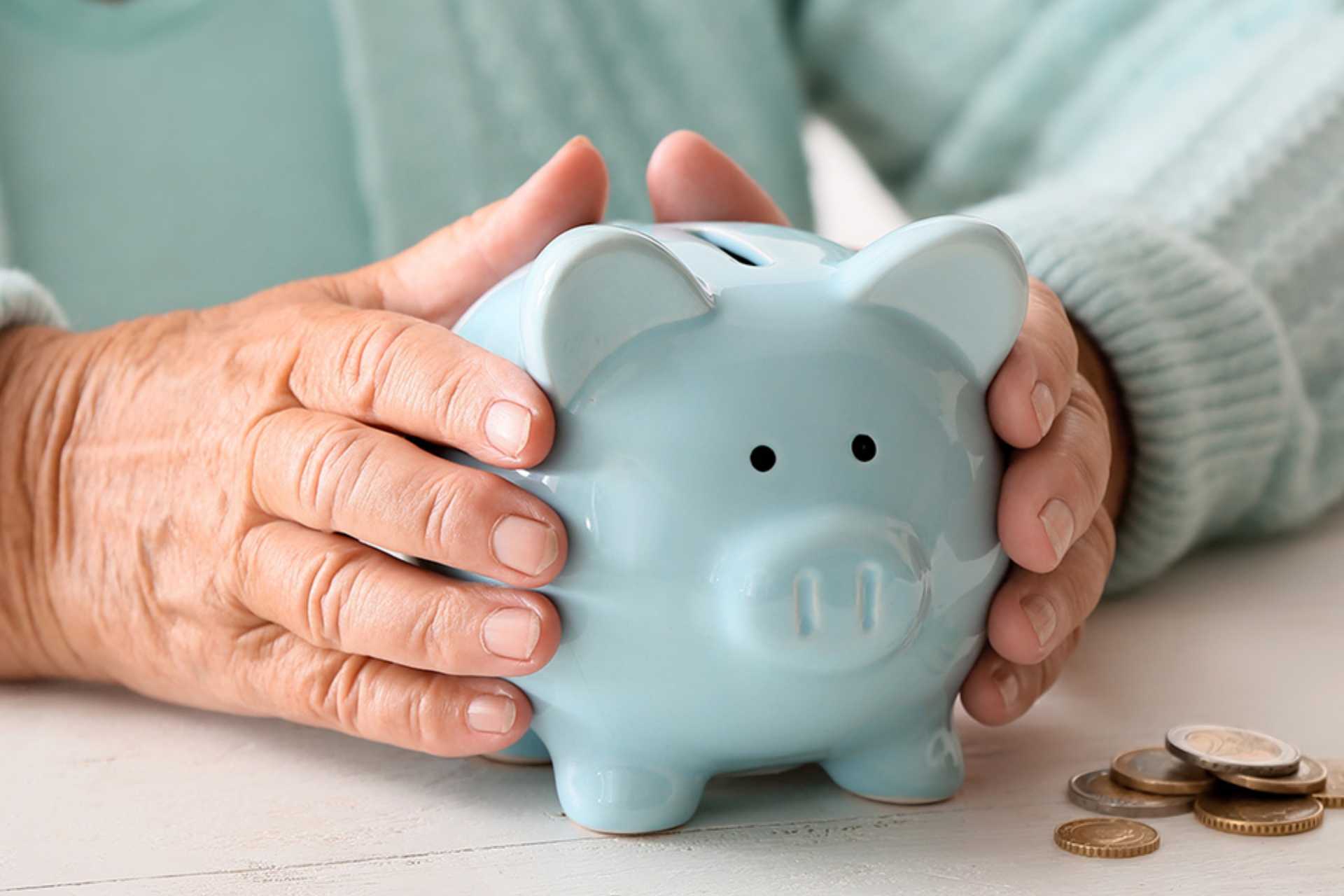 türkises Sparschwein zwischen alten Händen